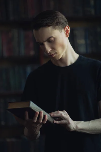 Portrait of a handsome pensive young man with a book in a room. Men's beauty and health.