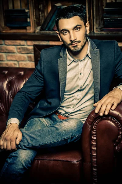 Portrait of a sexy handsome man on a leather sofa. Fashion shot. Men\'s beauty, fashion. Men\'s barbershop, Hairstyle.