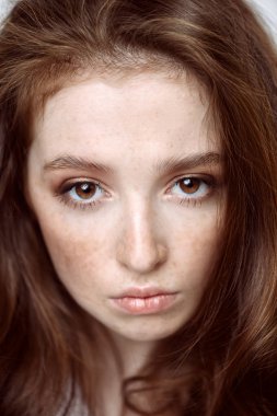 Yakın çekim beyaz arka plan üzerinde uzun kıvırcık kırmızı saçlı bir on beş yaşındaki kız portresi. Güzellik, moda.