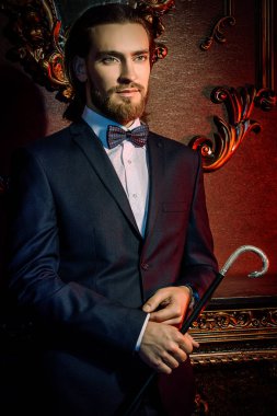Daireler lüks klasik iç ile poz şık elbiseli iyi giyimli bir heybetli adam portresi. Erkek güzelliği, moda. Saç şekillendirme, berber. 