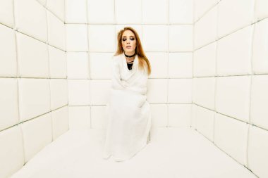 Tımarhane izole bir odada deli gömleği giymiş çılgın bir kız portresi.