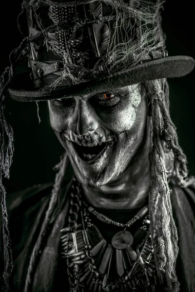 Close-up portrait of a man with a skull makeup dressed in a tail-coat and a top-hat. Baron Saturday. Baron Samedi. Dia de los muertos. Day of The Dead. Halloween.