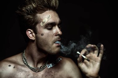 Antisosyal davranış, kötü alışkanlıkları. Sigara İçilmeyen bir kötü çocuk portresi. Rocker, serseri.