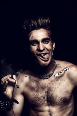 Antisosyal davranış, kötü alışkanlıkları. Sigara İçilmeyen bir kötü çocuk portresi. Rocker, serseri.