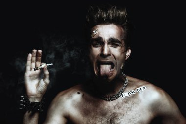Antisosyal davranış, kötü alışkanlıkları. Sigara İçilmeyen bir kötü çocuk portresi. Rocker, serseri.