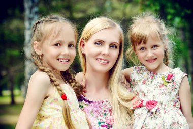 Parkta güzel kızları ile güzel bir mutlu anne portresi. Yaz tatili. Aile kavramı. 