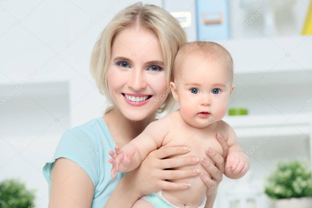 Portrait of a happy young mother with her small baby at home. Family concept. Healthcare, pediatrics.