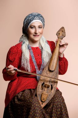 Yaşlı yerli kadın ulusal bir kostüm. Antik keman çalıyor.