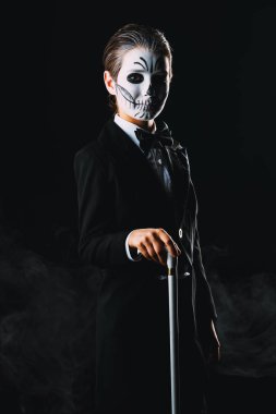 Bir çocuk çocuk portresi zarif kuyruk-ceket giyen bir iskeletin karnaval makyajlı. Studio siyah arka plan üzerinde vurdu. Cadılar Bayramı. Dia de los muertos. Ölülerin günü.