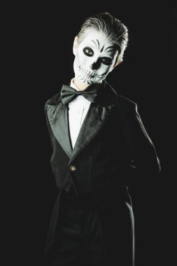 Bir çocuk çocuk portresi zarif kuyruk-ceket giyen bir iskeletin karnaval makyajlı. Studio siyah arka plan üzerinde vurdu. Cadılar Bayramı. Dia de los muertos. Ölülerin günü.