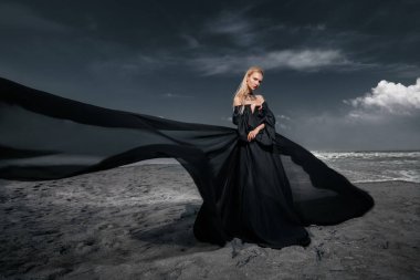 Tam uzunlukta portre güzel bir Gotik kadının uzun siyah elbise poz açık. Güzellik, moda.