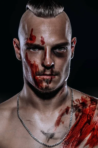 Fight club, MMA. Portrait of a bad guy fighter with a face in the blood, demonstrating his muscles and strength. Rocker, punk.