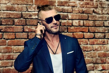 Yakışıklı işadamı şehir cep telefonuyla konuşuyor. Canlı aktif yaşam tarzı. Başarı. Erkek güzellik, moda. 