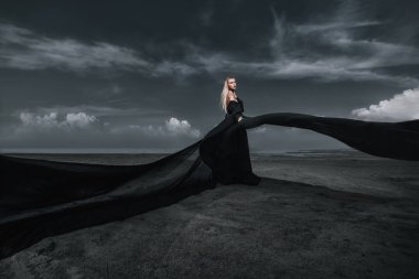 Tam uzunlukta portre güzel bir Gotik kadının uzun siyah elbise poz açık. Güzellik, moda.