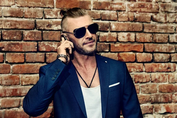 Yakışıklı işadamı şehir cep telefonuyla konuşuyor. Canlı aktif yaşam tarzı. Başarı. Erkek güzellik, moda. 