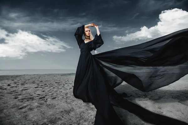 Tam uzunlukta portre güzel bir Gotik kadının uzun siyah elbise poz açık. Güzellik, moda.