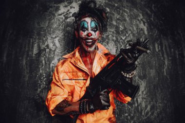 Deli şeytani palyaço adam kan lekeli bir puro sigara ve elinde bir silah. Cadılar Bayramı. Korku, gerilim filmi.