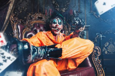 Şeytani palyaço adam kan lekeli bir odada vintage iç puro ile oturuyor. Cadılar Bayramı. Korku, gerilim filmi.