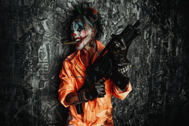 Deli şeytani palyaço adam kan lekeli bir puro sigara ve elinde bir silah. Cadılar Bayramı. Korku, gerilim filmi.