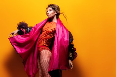 Vogue bir kadın model stüdyoda poz bir kadeh. Moda koleksiyonu. Portre sarı arka plan üzerinde.