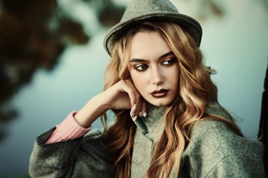 Romantik genç kadın güzel bir sonbahar park ağacın altında oturuyor. Güzellik, sonbahar moda.