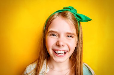Close-up portrait of a funny emotional girl making faces at camera. Studio shot over yellow background. Childhood concept. clipart