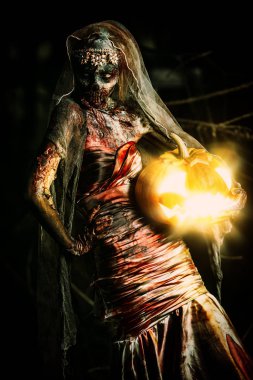 Cadılar Bayramı. Korkunç zombi gelini bir gece mezarlığı üzerinde bir balkabağı fener tutar. 