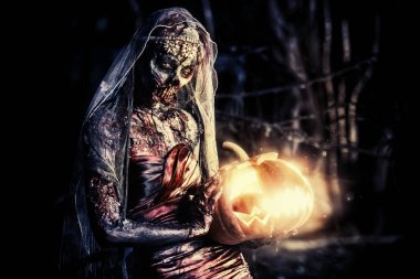 Cadılar Bayramı. Korkunç zombi gelini bir gece mezarlığı üzerinde bir balkabağı fener tutar. 