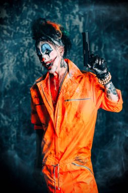 Deli şeytani palyaço adam kan lekeli bir silah düzenliyor. Cadılar Bayramı. Korku, gerilim filmi.