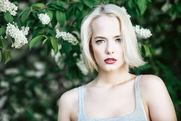Attractive young woman with blonde hair posing outdoor. Mood of spring and summer. Beauty, cosmetics.