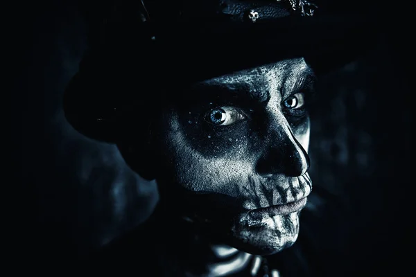 Close-up portrait of a man with a skull makeup dressed in a tail-coat and a top-hat. Baron Saturday. Baron Samedi. Dia de los muertos. Day of The Dead. Halloween.