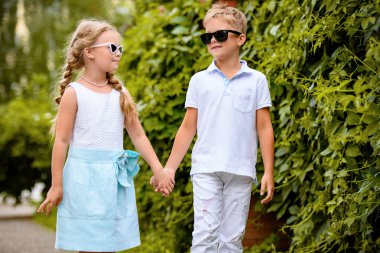 Çocuklar parkta yürüyorlar. Çocukluk, yaz. Moda kavramı.