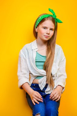 Children's fashion. Beautiful  little girl posing at studio over yellow background. clipart