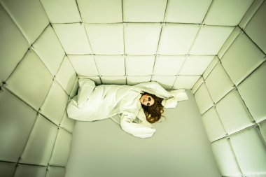 Tımarhane izole bir odada deli gömleği giymiş çılgın bir kız portresi.