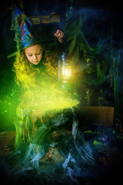 Cadılar Bayramınız Kutlu Olsun. Şirin çocuk cadı kostüm bir cadının ininde kızıdır. Sihirli bir iksir şirin neşeli küçük cadı aşçılar. 