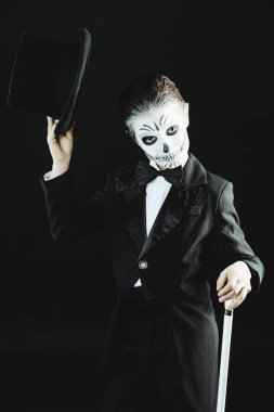 Bir çocuk çocuk portresi zarif kuyruk-ceket giyen bir iskeletin karnaval makyajlı. Studio siyah arka plan üzerinde vurdu. Cadılar Bayramı. Dia de los muertos. Ölülerin günü.