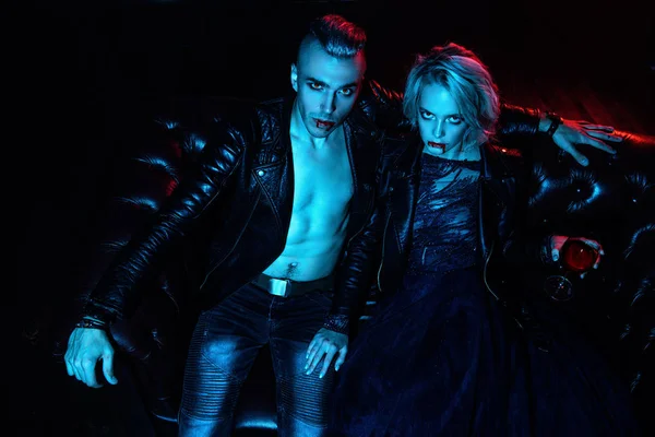 A beautiful couple of vampires is sitting in a dark room. Beauty, fashion.