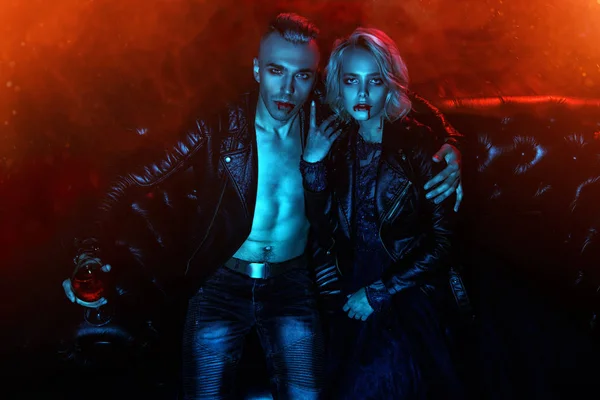 A beautiful couple of vampires is sitting in a dark room. Beauty, fashion.