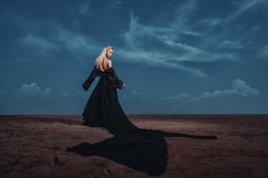 Tam uzunlukta portre güzel bir Gotik kadının uzun siyah elbise poz açık. Güzellik, moda.