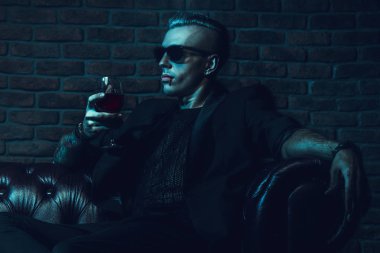 Bir vampir adam gözlüklü karanlık bir odada oturuyor ve şarap içme. Klasik tarzı. Güzellik, moda.