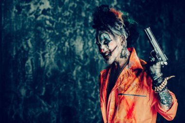 Deli şeytani palyaço adam kan lekeli bir puro sigara ve elinde bir silah. Cadılar Bayramı. Korku, gerilim filmi.