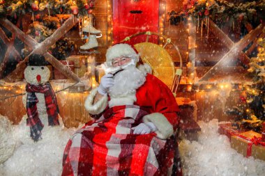 Noel Baba bir battaniyeye örtülü ve pipo bir sandalyede oturuyor. Noel Baba'nın evi. Noel dekorasyon. 