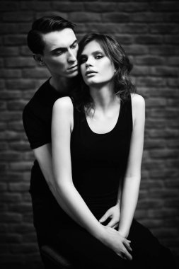 Güzel genç bir çift bir tuğla duvara yakın poz aşık. Güzellik, moda.