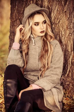 Romantik genç kadın güzel bir sonbahar park ağacın altında oturuyor. Güzellik, sonbahar moda.