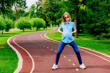 Hamile kadın parkta egzersizleri yapıyor. Gebelik. Sağlıklı yaşam tarzı.