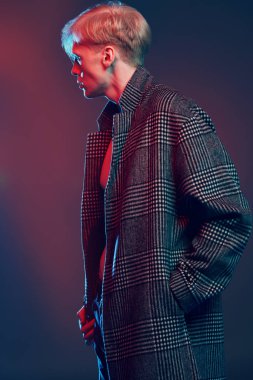 Stüdyoda gri arka plan üzerinde poz yakışıklı bir genç adam sarışın saçlı ekose bir palto giyiyor portresi. Erkek güzellik ve sağlık.