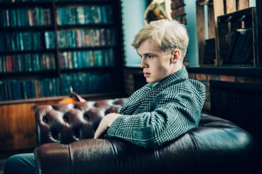 Deri koltuk üzerinde seksi yakışıklı bir adam portresi. Moda vurdu. Erkek güzelliği, moda. 