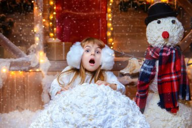 Kız şirin çocuk Noel için dekore edilmiş evinin yakınındaki bir kardan adam sculpts. Mutlu Noeller ve mutlu yeni yıl.