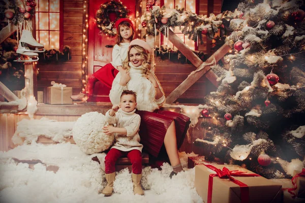 Mom with children posing on the porch of the house, decorated for Christmas. Merry Christmas and Happy New Year.