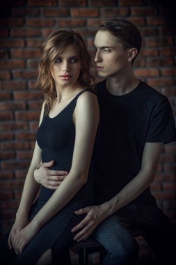Güzel genç bir çift bir tuğla duvara yakın poz aşık. Güzellik, moda.